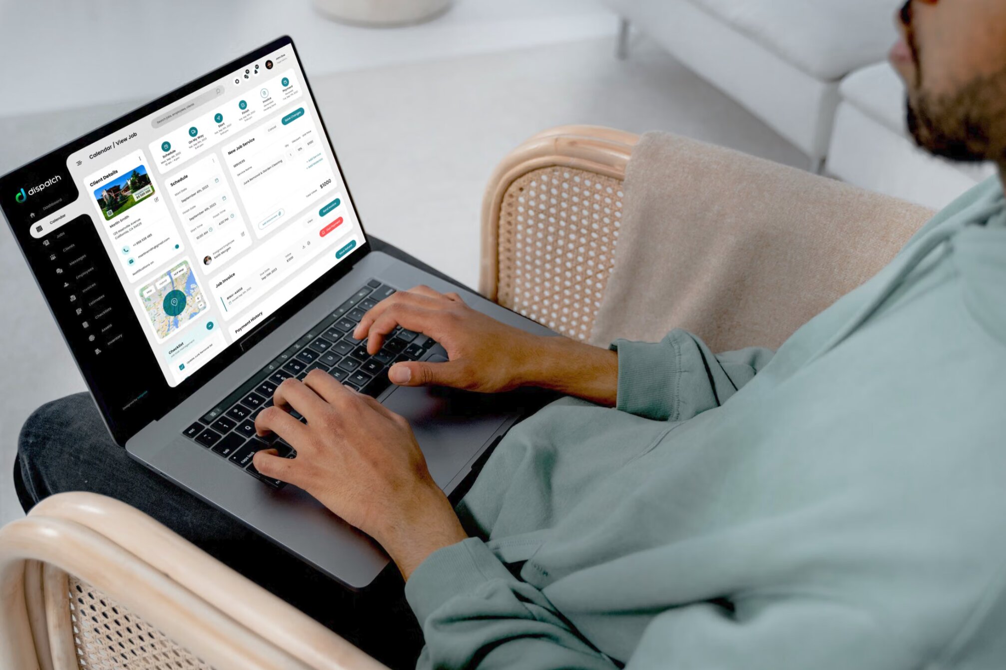 A man in an armchair with a Dispatch job page open on his laptop: client details, the job’s six steps, its schedule, services and invoice